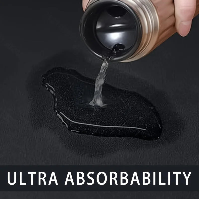 Eine Hand gießt Flüssigkeit auf eine schwarze Abmatte, die Ultraabsorbierbarkeit demonstriert.