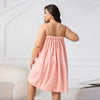 Femme portant une jupe de bain rose texturée et un bonnet de douche assorti, vue de dos.