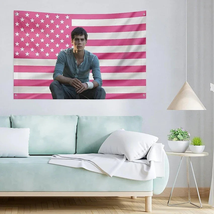A man sits in front of a patriotic American flag tapestry featuring red, white, and blue stripes and stars.