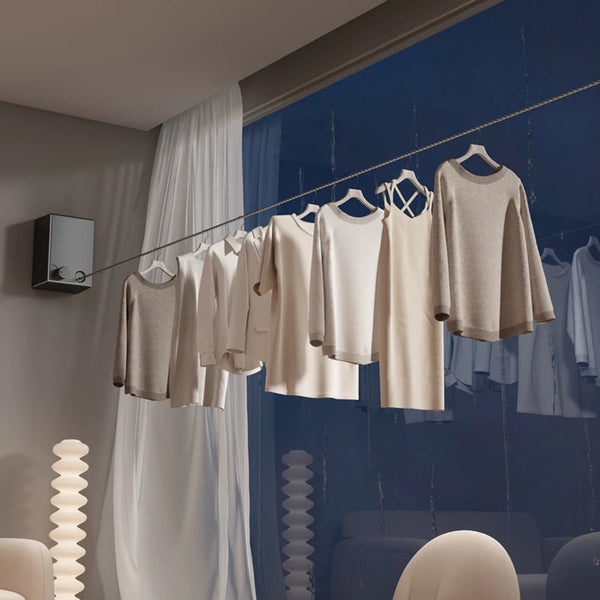 A rack of light beige and white clothing hanging on a retractable stainless steel clothesline against a dark blue background.