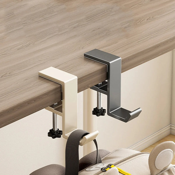 A close-up view of an aluminum desk hanging hook mounted on a wooden desk surface.