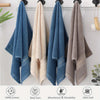 A set of three fluffy bath towels in blue, beige, and gray hanging on a white wall.