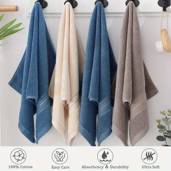 A set of three fluffy bath towels in blue, beige, and gray hanging on a white wall.