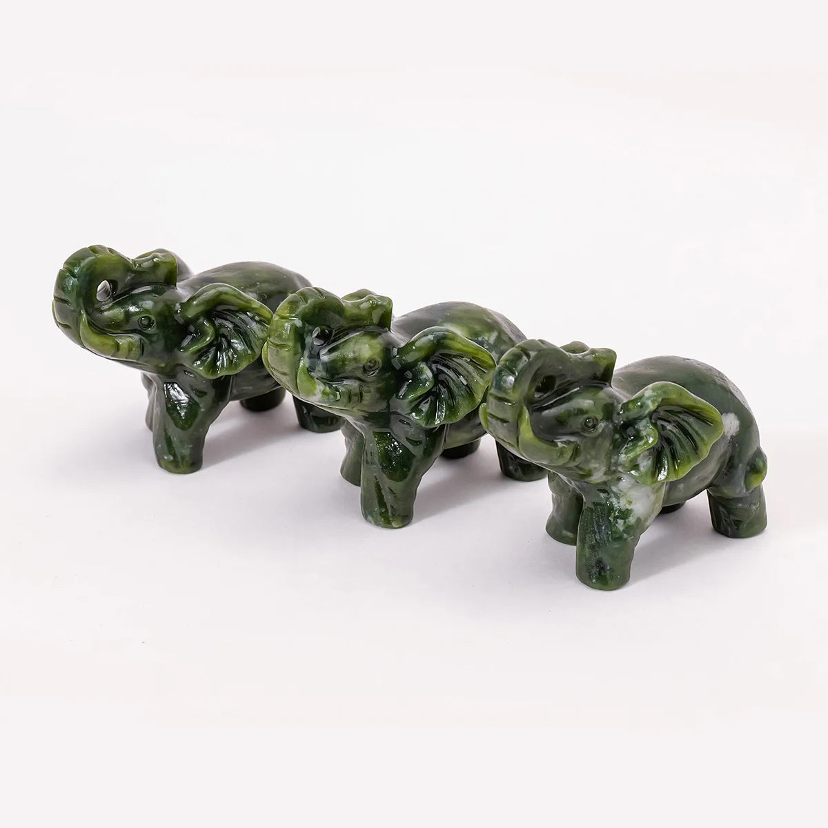 Hand-carved jade elephant statue in green, displayed against a white background.