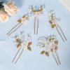 A set of delicate pearl and gold floral bridal hair clips arranged on light blue fabric.