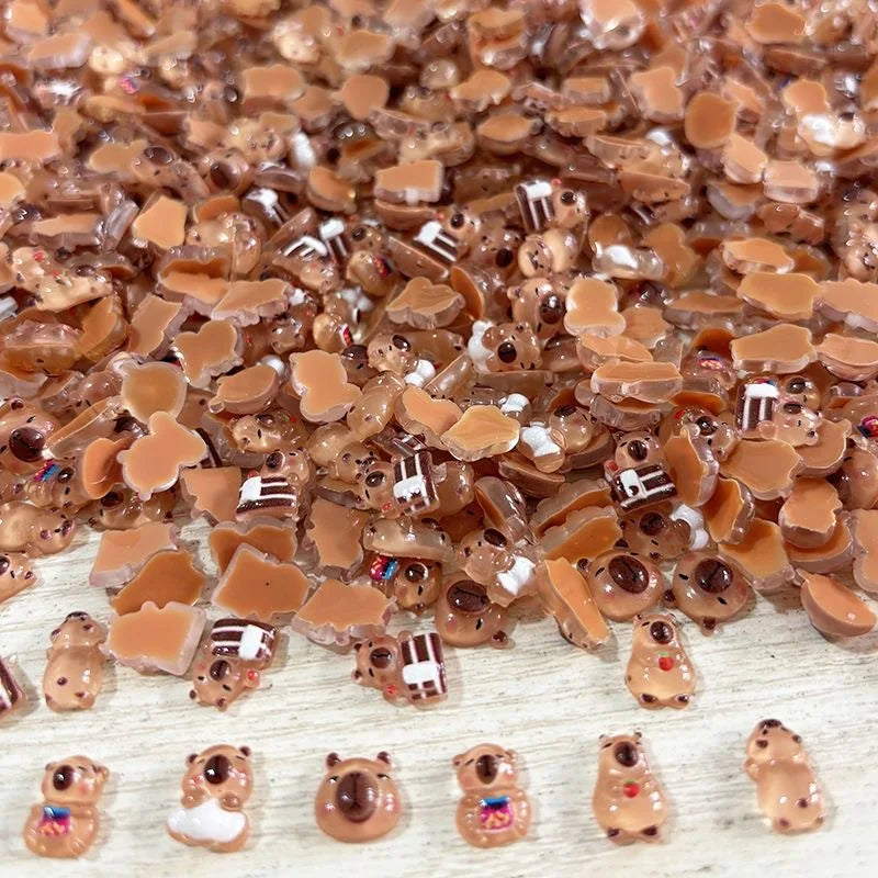 Nahaufnahme kleiner, braun-ockerfarner Capybara-Figuren auf einer hellen Holzoberfläche.