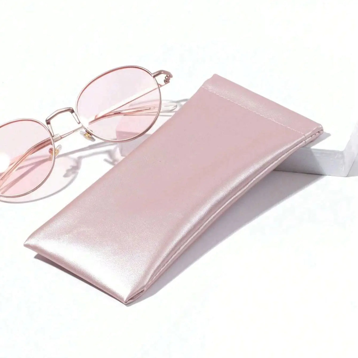 A pink PU leather squeeze eyeglasses case with a soft lining and a pair of matching pink-tinted sunglasses.