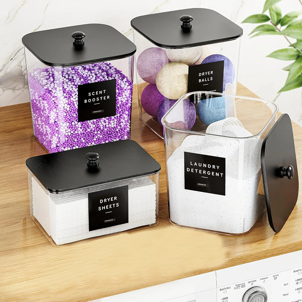 A set of three clear plastic laundry storage containers with black lids filled with dryer balls, dryer sheets, and laundry de