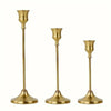 A set of three elegant brass metal candle holders with flared bases and slender stems.