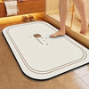 A white diatomite bath mat with a brown border and a small flower design placed on a tiled floor.