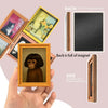 A hand holds a framed picture of a 3D monkey with dark skin and curly hair, showing the front and back details.