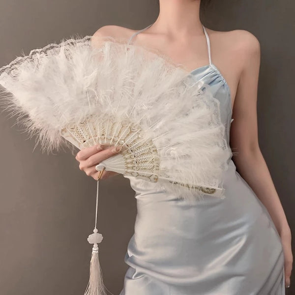 A woman holds a large, white vintage folding hand fan against a gray background.
