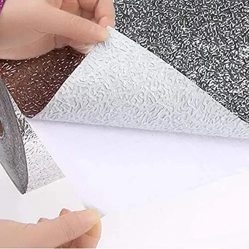 Rolls of self-adhesive aluminum foil kitchen wall stickers in various patterns being prepared for application.
