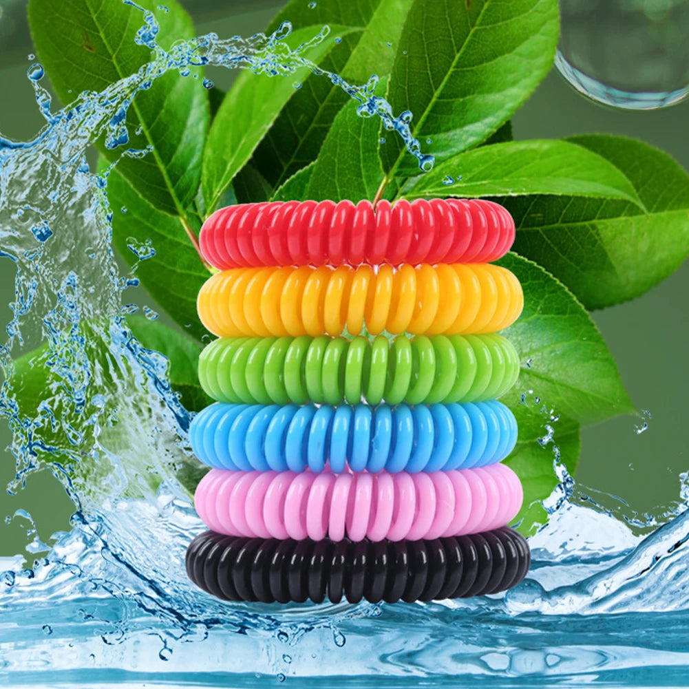 A stack of ten colorful silicone bracelets in rainbow order, being washed by water amidst green leaves.