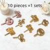 A collection of ten gold and rose gold acrylic birthday cake toppers arranged on a white marble surface.