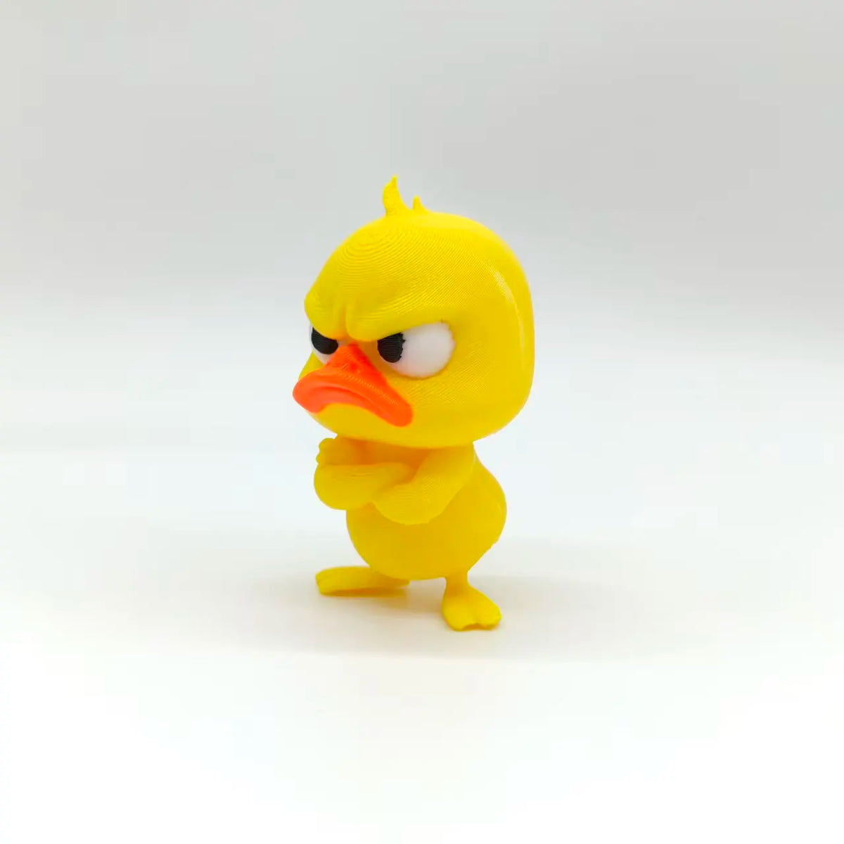 Statue de canard imprimée en 3D jaune avec une expression fâchée et un bec orange.