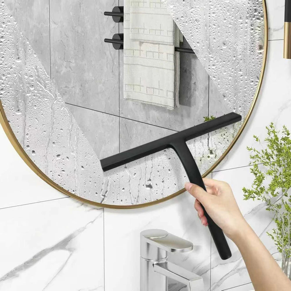Eine Hand benutzt einen schwarzen Silikonschrubber, um einen runden Glastiegel im Badezimmer zu reinigen.
