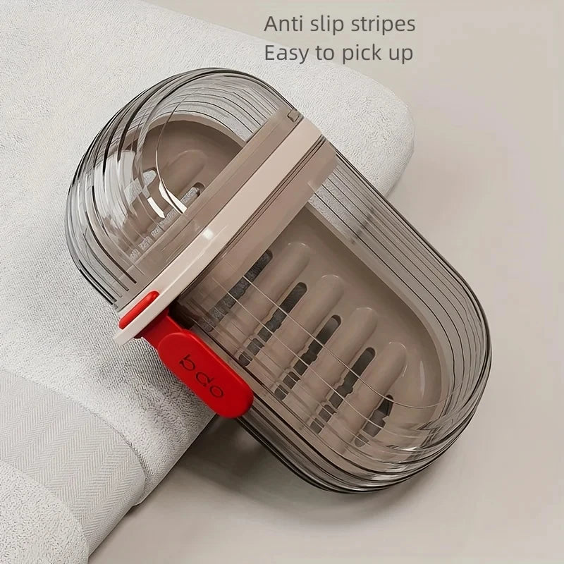 A clear silicone soap dish with anti-slip stripes and a white lid is shown on a white towel.
