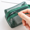 A hand is opening a green mesh storage bag to show the transparent interior and zipper.