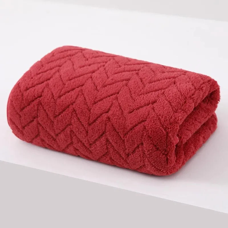 A deep coral red velvet bath towel with a textured diamond pattern rolled up.