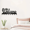 Black decorative metal key holder rack with hooks mounted on a white wall.