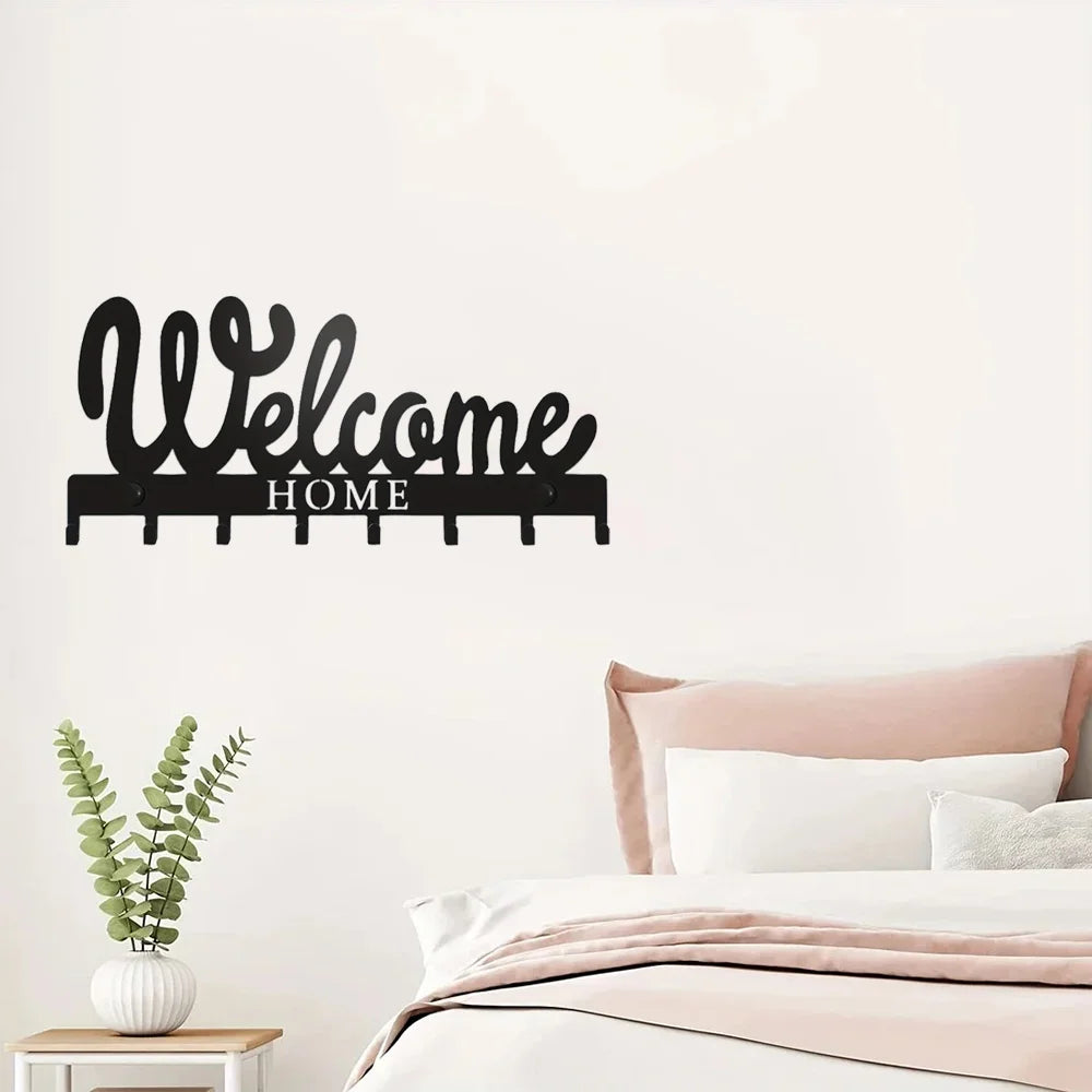 Black decorative metal key holder rack with hooks mounted on a white wall.