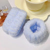 A set of light blue microfiber wrist sweatbands for face washing and skincare placed on a white surface.