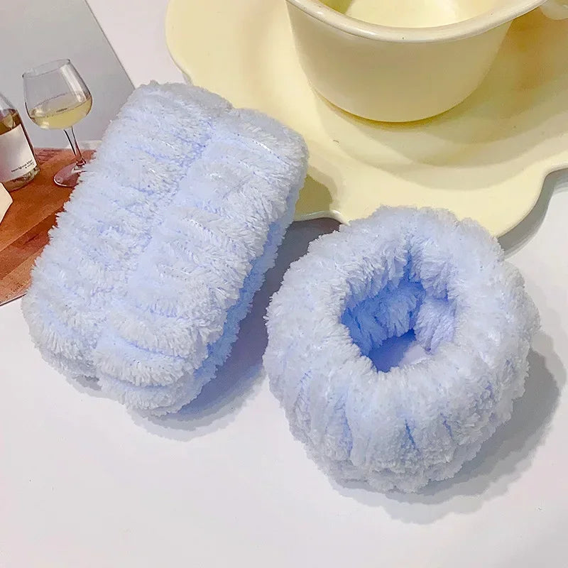 A set of light blue microfiber wrist sweatbands for face washing and skincare placed on a white surface.