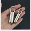 A hand holds a stainless steel travel pill box and first aid container with hinged lids.