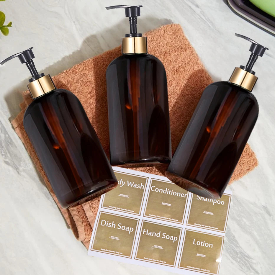 A collection of dark amber refillable pump soap dispenser bottles and a paper label are displayed on a light surface.