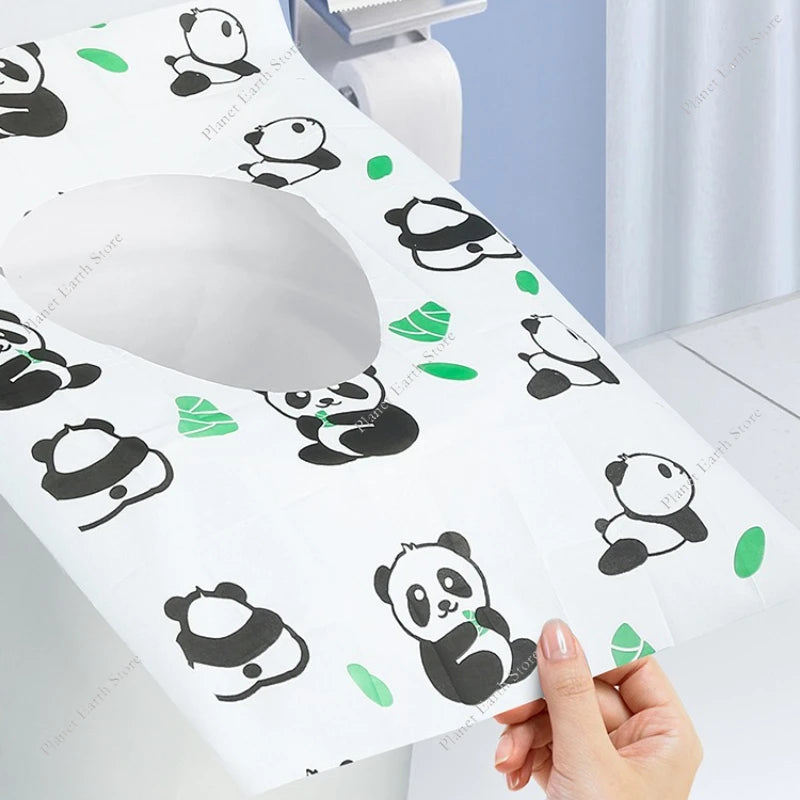A hand holds a white disposable printing seat cover featuring black panda designs on a light blue surface.