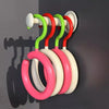 Un rack d'accroches colorées et flexibles dans des tons de vert, rouge et rose, fixé à un mur sombre.