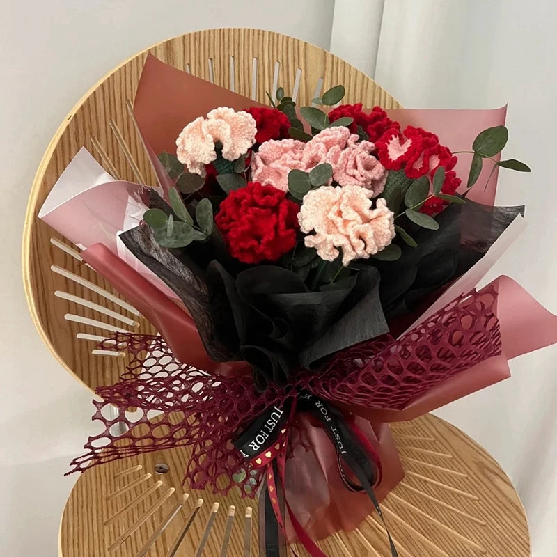 Un bouquet de cœurs de coton faits main, roses et rouges, emballés dans du papier foncé et attachés avec un ruban de dentelle
