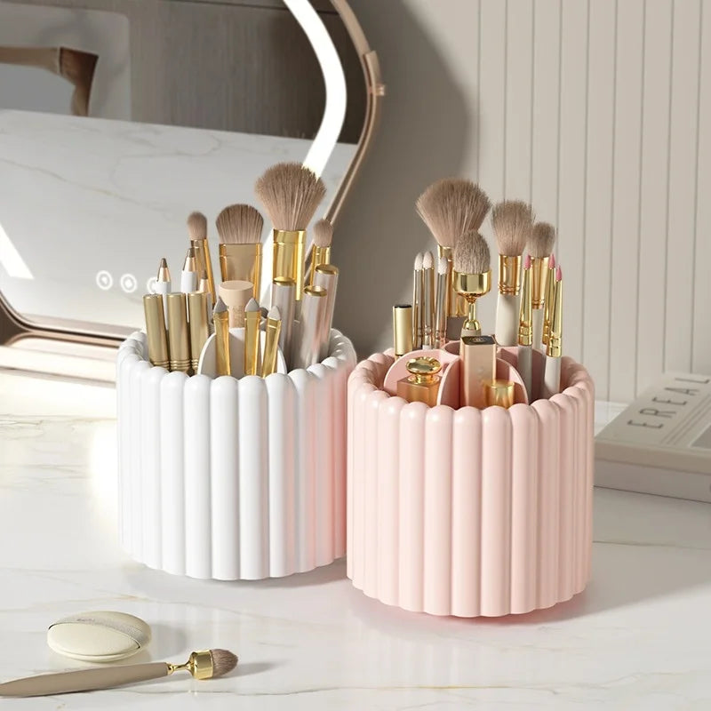 A pink and white cylindrical organizer holding various makeup brushes and tools next to a lighted vanity mirror.