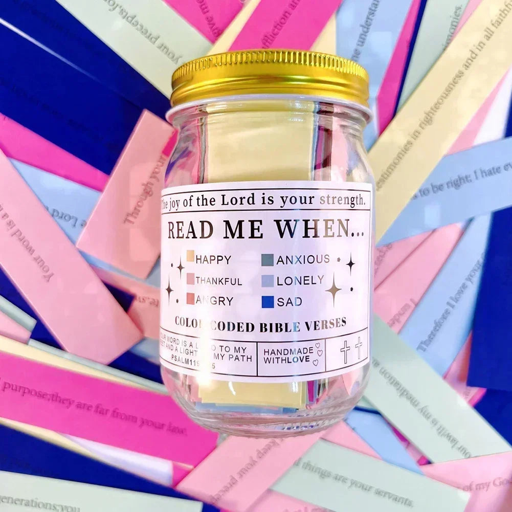 A glass jar filled with colorful scripture verses and a gold lid, set against a background of pink and blue paper.