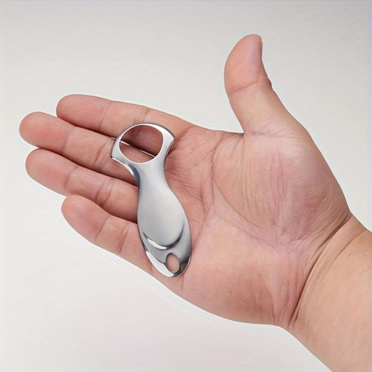 A hand holds a stainless steel tongue scraper with a protective case.