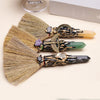 Three natural crystal points with gold accents and various colored stones displayed on a light background.