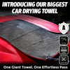 A close-up of a large gray microfiber car drying towel being used on a red car surface.