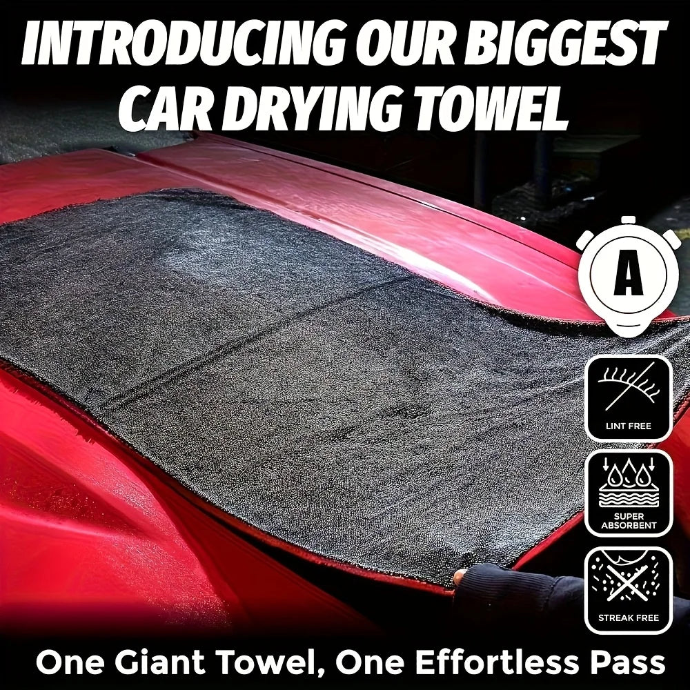 A close-up of a large gray microfiber car drying towel being used on a red car surface.