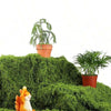 An artificial moss garland is displayed on a green textured surface with a small potted plant and a small orange squirrel.