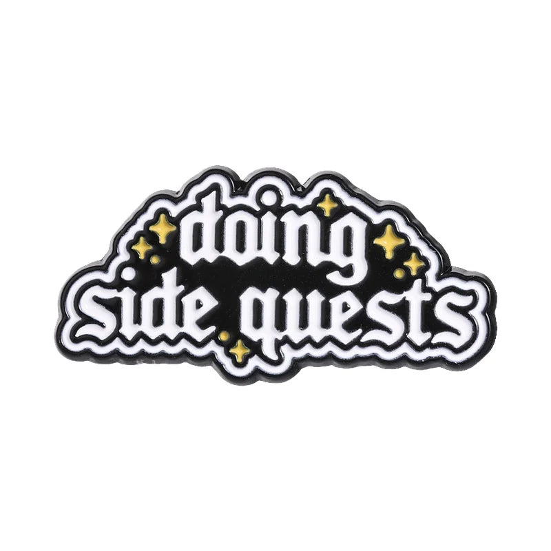 Black enamel lapel pin featuring the text Doing Side Quests in gold lettering with star accents
