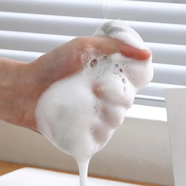 A hand is squeezing a thick, white foam or lather onto a surface.