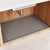 A silicone under sink waterproof mat is installed in a wooden cabinet with a stainless steel faucet.