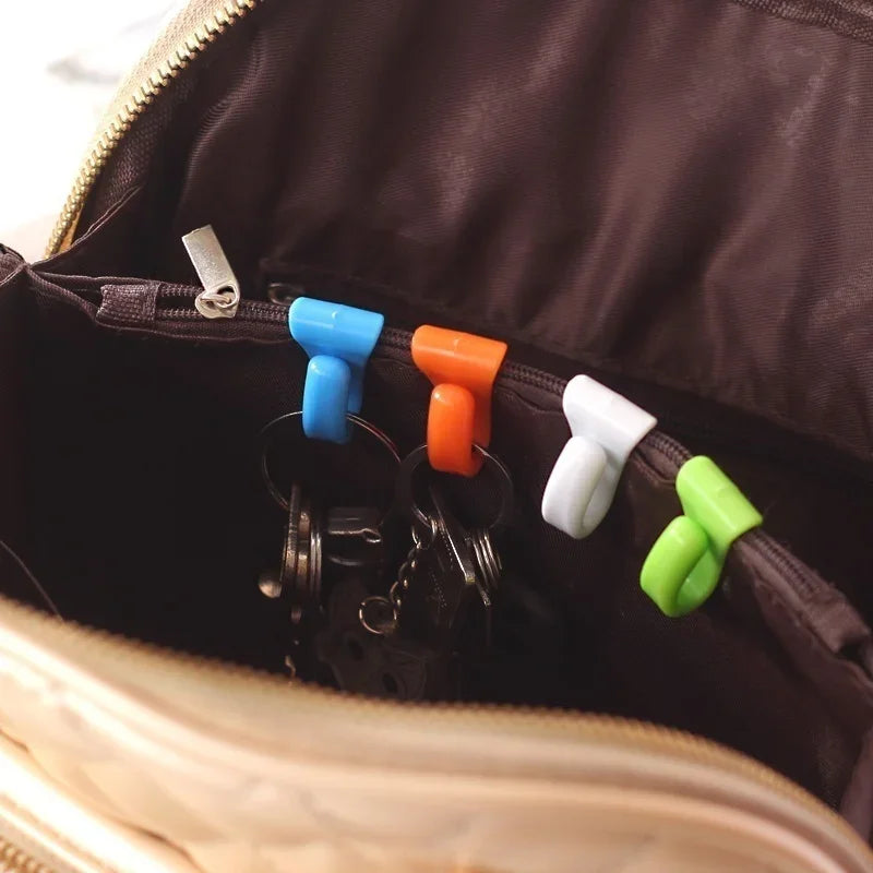 A close-up view inside a dark brown bag showing a pack of four colorful key holder clips.