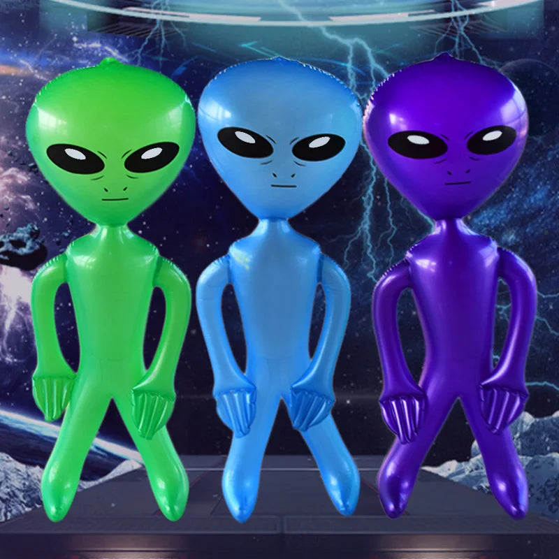 Three inflatable alien decorations in green, blue, and purple standing on a dark surface.