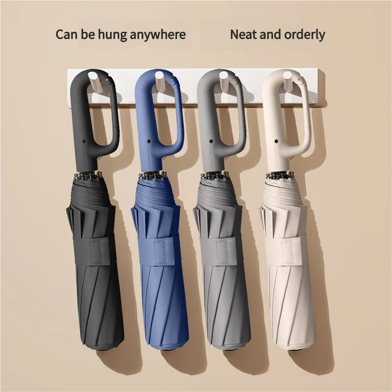 Three windproof automatic folding umbrellas in gray, blue, and white hanging on a wall.