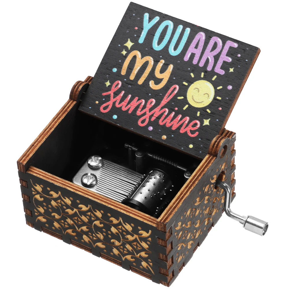 A vintage engraved wooden music box with a lid featuring the text YOU ARE my sunshine and a silver key.
