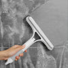 Eine Hand hält einen weißen 3-in-1 Fensterreinigungs-Squeegee und Wischer-Set vor einer grauen, strukturierten Oberfläche.