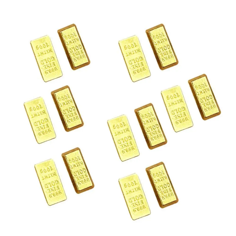 A collection of small gold bar decorative ornaments scattered across a white background.