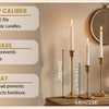 A set of six gold weighted metal taper candlestick holders displayed on a wooden surface.